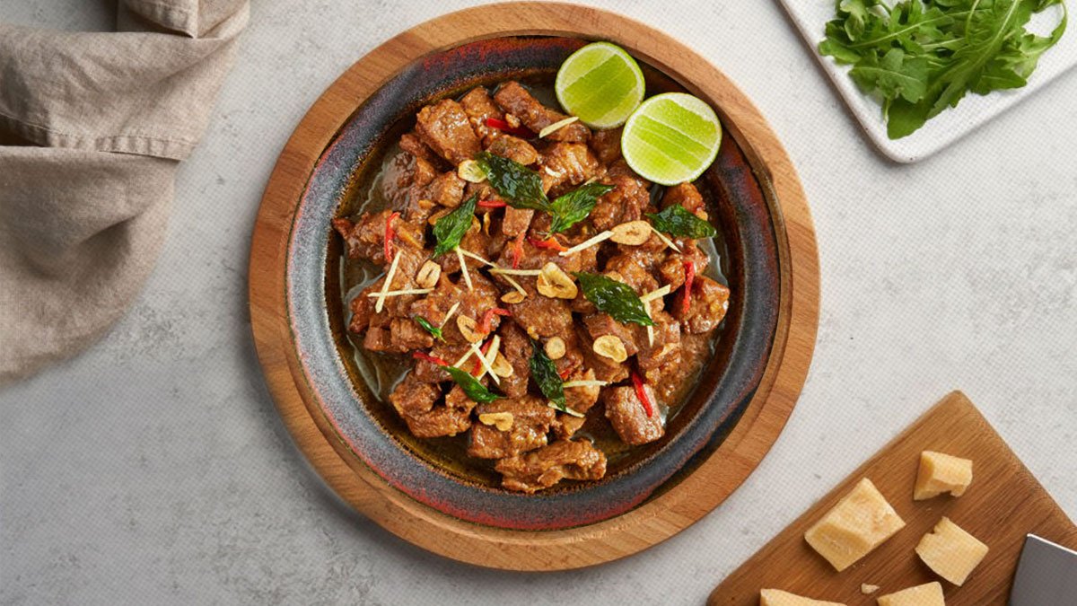 A delicious serving of tamarind rum pork braise, featuring tender pork in a rich, savory sauce garnished with herbs.